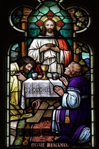 Stain glass window with Jesus breaking bread.