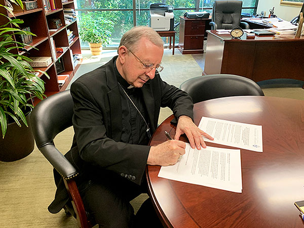 Bishop Konzen signing a letter about the 2020 Census