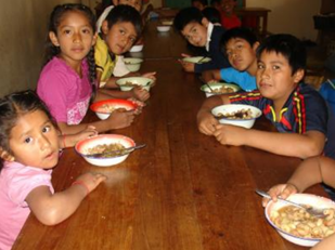 Children sitting at a table eating a meal.